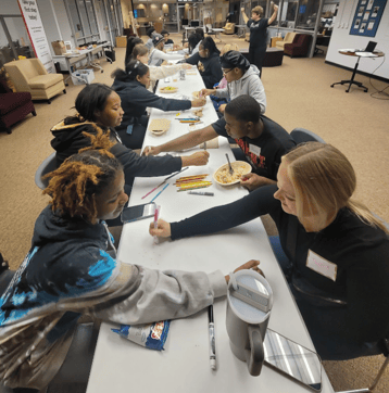 Oakland Table Activity students writing at First-gen event