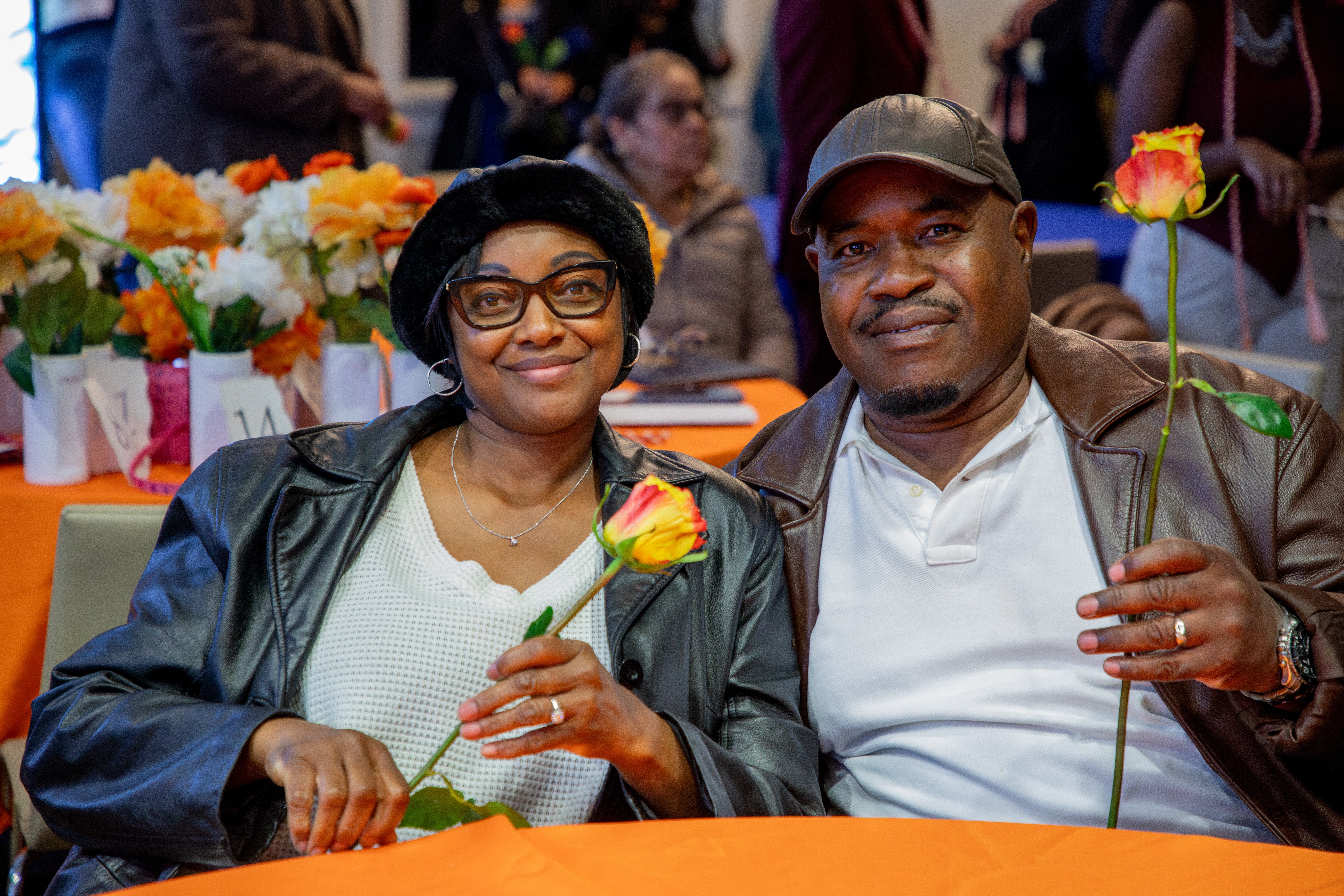 Two adults at a table holding roses as family of first-gen students.