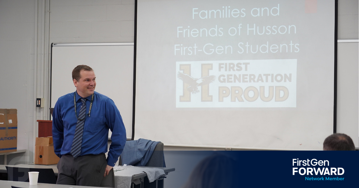Male Speaker wearing a blue button up shirt in front of classroom before First-Gen Presentation
